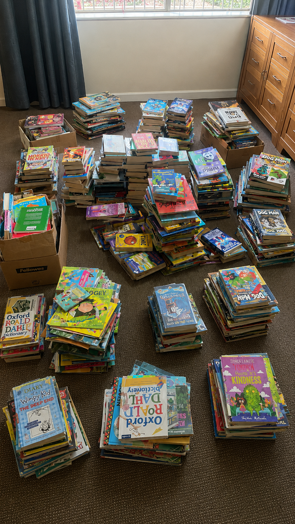 Stacks of books donated by St John's College sorted for Next Chapter Jozi literacy work