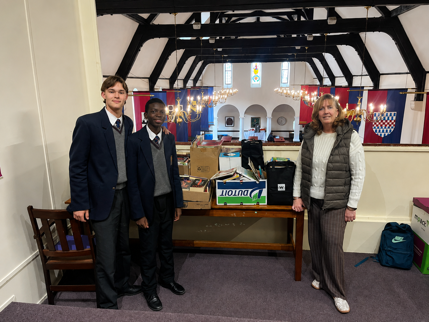 Jesse Lang, Jenovic Lumu and Sue Rabie standing with donated books at St John's College